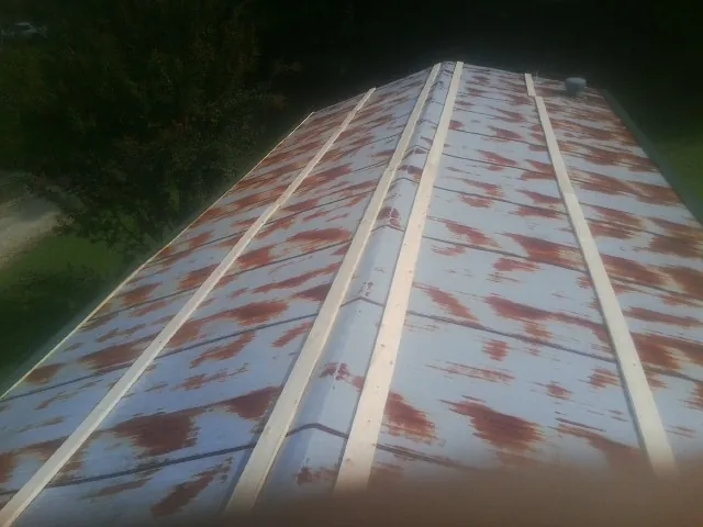 Rusted metal roof panels with new wood purlins before replacement — Storm Damage Roof Repair in Delevan by Roofing Brothers