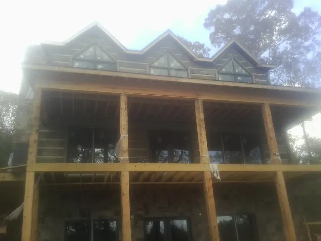 Dormers and porch framing on a large log home under construction — Roof Coating work by our crew in Delevan