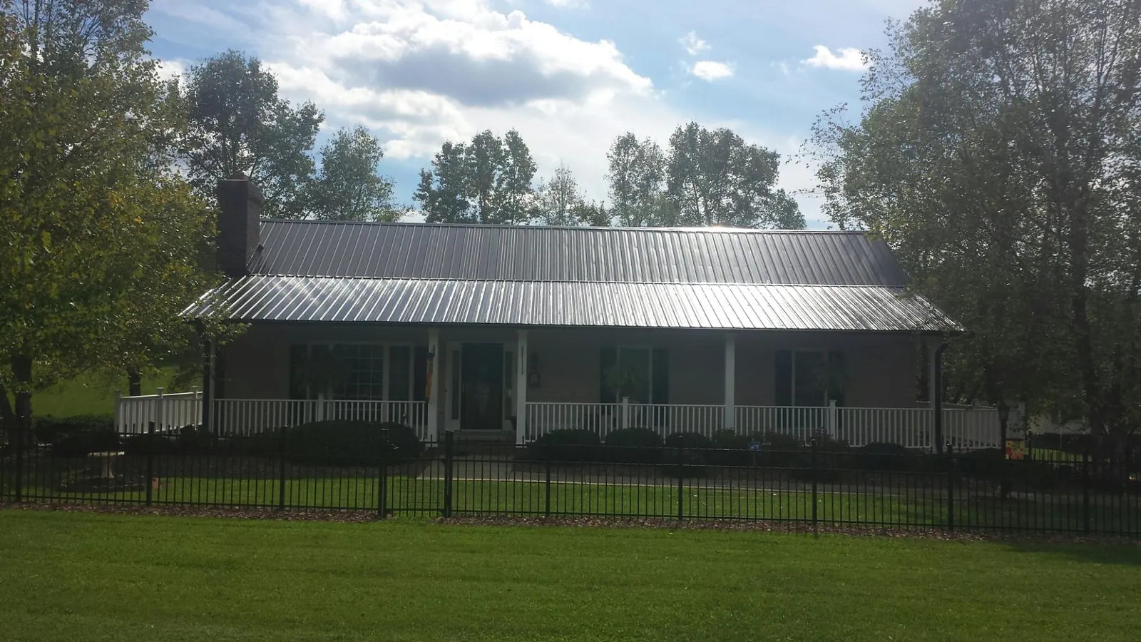Gray metal roof on a brick ranch with a full width front porch — Gutter Guard Installation work by our crew in Delevan